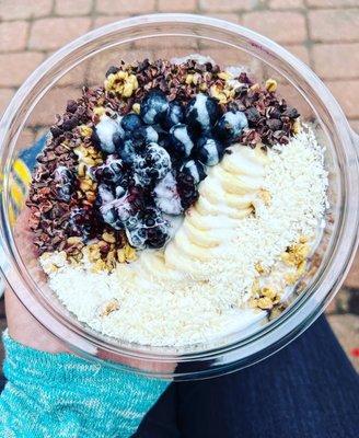 Acaí bowl with banana, blackberry, blueberry, granola, cacao nibs, coconut, and a coconut honey cream drizzle.