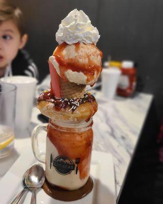 Vanilla donut shake with strawberry sauce. Has a whole donut and and ice cream cone.