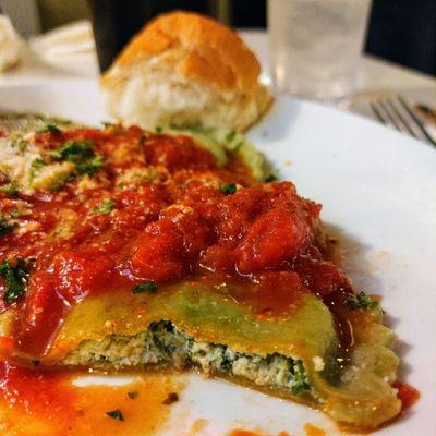 Inside view of the stuffed spinach and cheese ravioli, with bread in the background