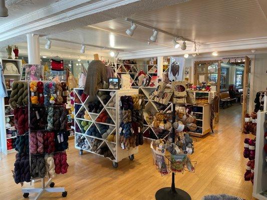 Inside view of yarn store with shelves and wire racks of yarn and kits