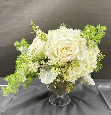 White roses, white hydrangea, with beautiful greenery in a brandy glass.