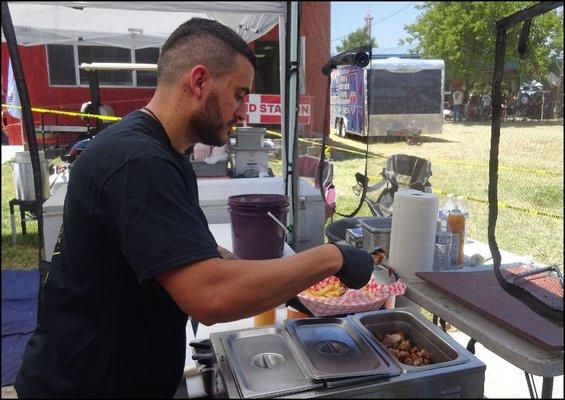 Mr. Chef preps my order of fries, as he adds delicious grilled sausage.