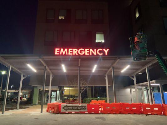 Installation-in-progress of an 'EMERGENCY' wayfinding sign at Braselton, GA's urgent care facility.