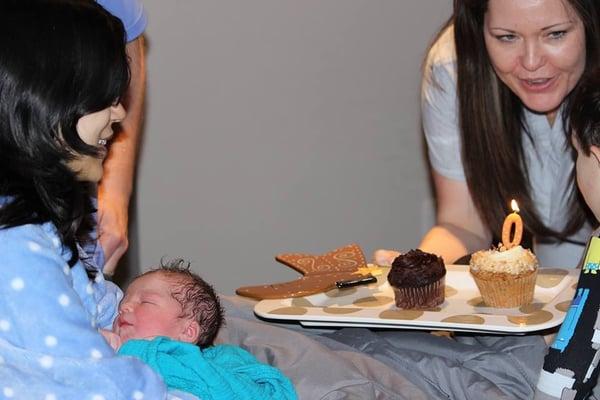 Nurse Midwife, Carla, singing happy birthday to my newborn shortly after birth and letting my older son blow out the candles.