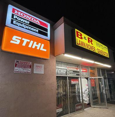 B&R Lawnmower and Generator at night. Brightly lit signs displaying Honda Power Equipment and Stihl garden equipment dealer status.