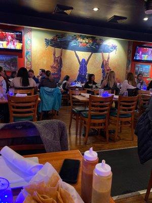 Mural on the wall, chips in the foreground, tv screens