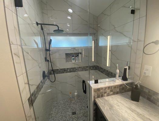 Custom shower remodel with frameless doors, Marble tops, bench seat and recessed shampoo shelf with awning window.