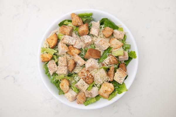 Chicken Caesar Salad. Diced seasoned Italian chicken breast, home-made herbed croutons, parmesan cheese with a side of caesar dressing.