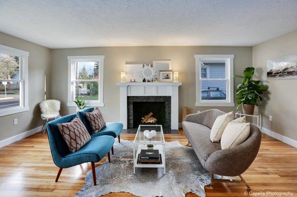 Staged living room with brown sofa and teal chairs.