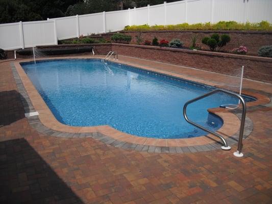 Roman end vinyl liner with brick coping, paver patio, double retaining walls and duel heaters