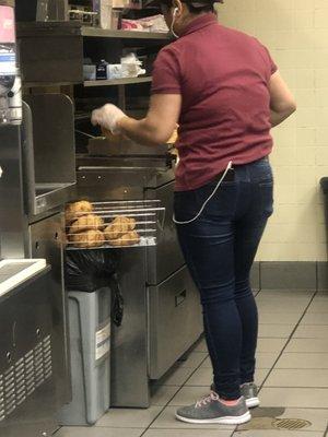 Photo of employee breaking health regulations by placing fresh crossiant on a dirty garbage pale.