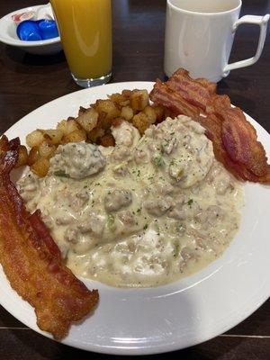 Biscuits and gravy, hash browns with a side of bacon.