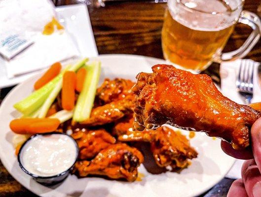 Single order 10 Buffalo wings (dirt style) with veggie sticks, bleu cheese dipping sauce and an ipa - drummette close up