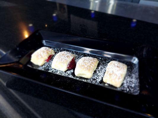 Raspberry stuffed beignets topped with confectioner sugar.