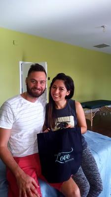 A happy couple smiles for the camera after being the demo table at Love Institute's Couples Massage Class.