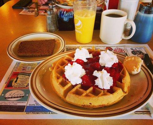 Belgian Waffle with strawberries and whipped cream, with a side of scrapple. OJ and Coffee to drink.