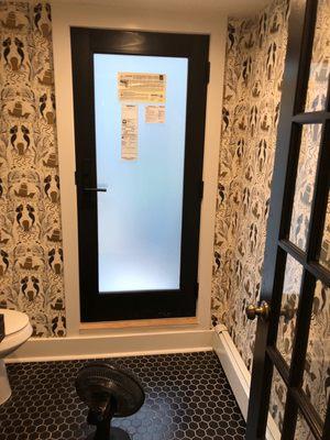 Cream gold black mermaid papered walls tiled floor with black door and octagon tile floors.