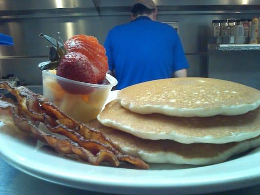 Triple Stack of Pancakes with some bacon and fresh fruit