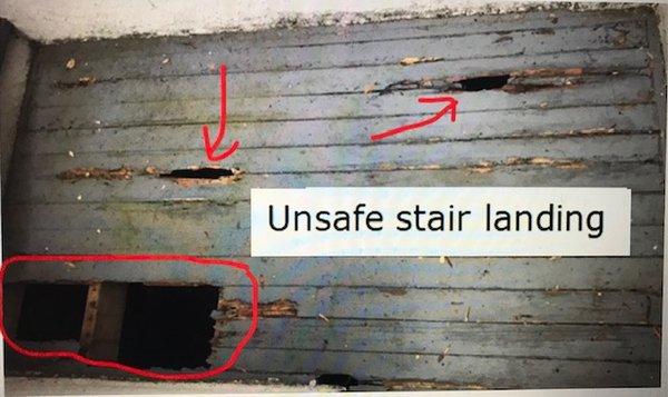 unsafe stair landing with gaping holes from dropped asbestos tiles