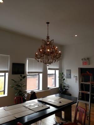 This huge chandelier needed 3 men to hang, a ladder secured on conference table (North Side of Williamsburg)