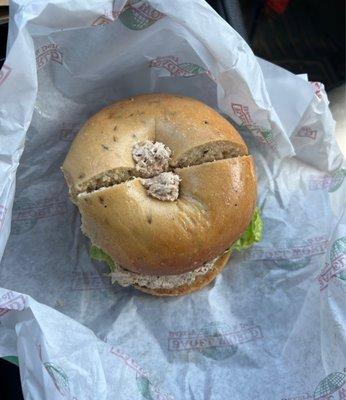 Tuna on a Rye bagel with lettuce tomato and onion.