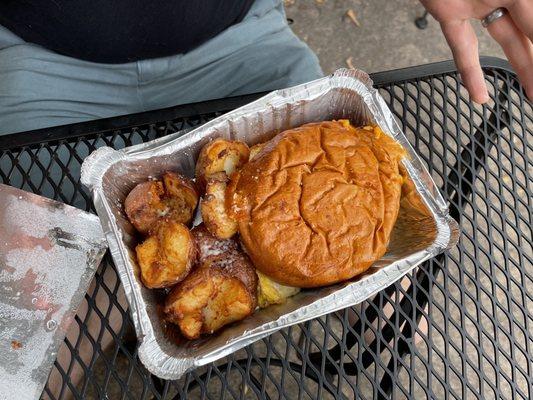 Breakfast sandwich with bacon and side of potatoes