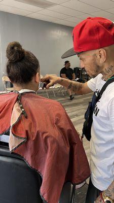 Pichon**The barber, focused on cutting one of the kid's hair, demonstrating his skills