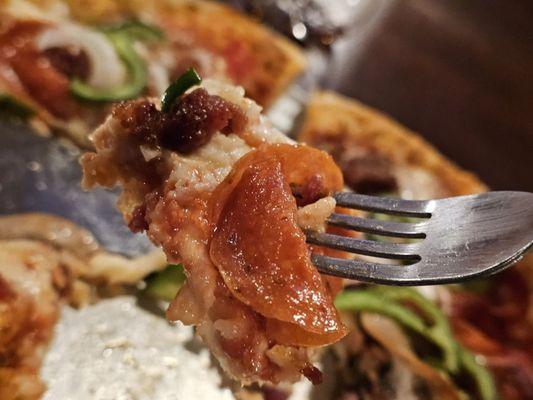 Close-up of a fork holding a piece of the Pizza Suprema.