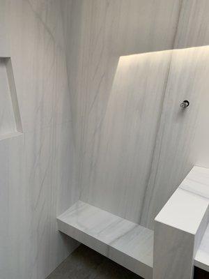 Custom mitered pony wall and shower bench in porcelain.