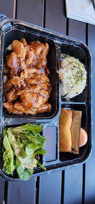 Chicken teriyaki bentonite box with eggrroll, rice, salad, and macaron