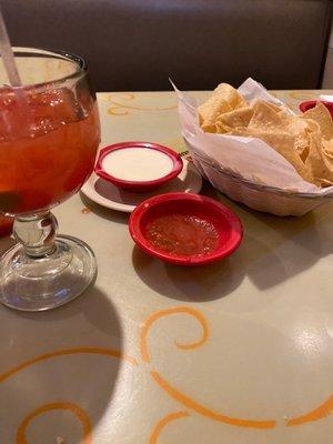 Cheese dip salsa and chips with a margarita