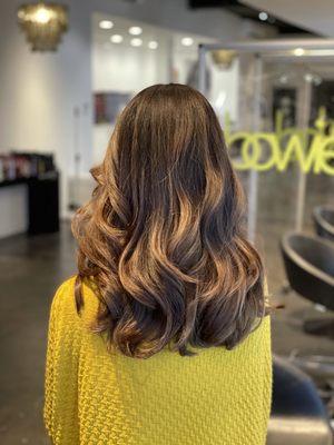 Brunette color with soft highlights and a haircut that creates movement and depth by Stacie