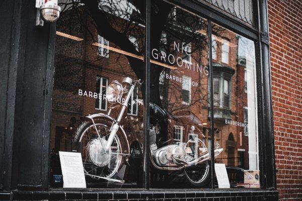 Nic Grooming Barbershop Pine Street's
 storefront, featuring our 1970 Norton 750 Commando S Model.