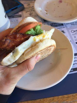 Bacon, egg, lettuce, and tomato on a toasted English... Blueberry muffin crumbs on background plate