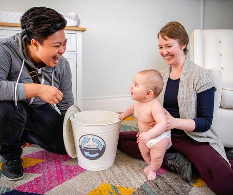 Two moms with baby and diaper pail to collect compostable diapers