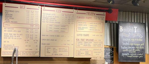 Menu board shows hot, iced and frozen drinks on the cream colored background, breakfast taco and oatmeal options on the blackboards.