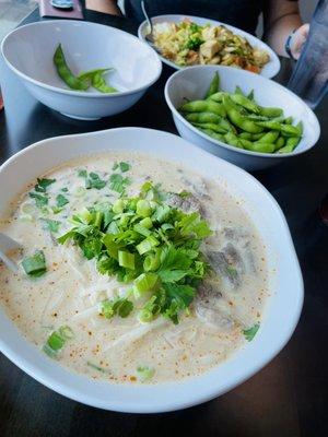 Beef Tom kha noodle soup (front plate), edamame, and pad see ew (back plate)