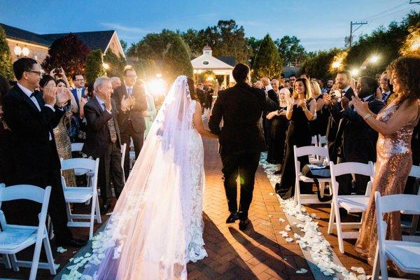 Guests applaud new bride and groom at outdoor wedding