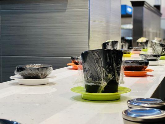 The dishes that are on a magnetic conveyor belt that goes up and down where you can pick up sides of vegetables to put in your soup.