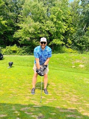 Midwest Select employee benefits insurance agent, Curtis Deprey, happily hitting a charity golf ball with hockey gloves on.