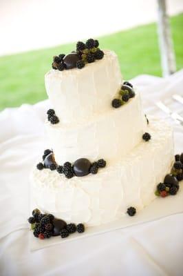 Stucco Italian buttercream icing and decorated with fresh black berreis, black plums, and black grapes.