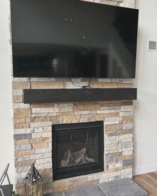 82" Samsung TV mounted on a brick wall, above a gas fireplace.