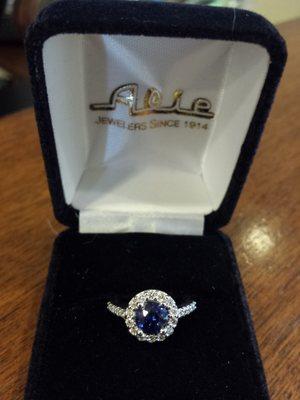 Custom-made blue sapphire diamond halo engagement ring made by Alie Jewelers.