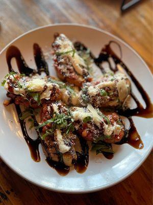 Bruschetta, 5 crostinis covered with pesto and tomatoes, garlic, basil, ricotta, mozzarella, and Parmesan then glazed with balsamic.