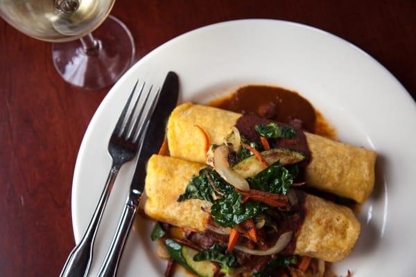 Gringas con Molé: our corn tortillas spread w/ garbanzo-white bean, filled w/ local pork or fresh local veggies & topped w/ our mole sauce.