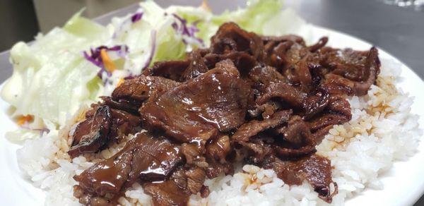 Beef Teriyaki. Grilled slices of tender beef atop a bed of steamed white rice and a side salad topped with hour homemade poppyseed dressing.