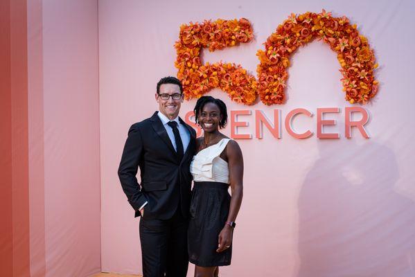 Couple pose in front of step and repeat banner