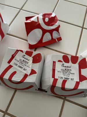 (In bag) spicy Chick-fil-A Sandwich. (In boxes left to right) Chick-fil-A Chicken Sandwich, Spicy Deluxe Sandwich