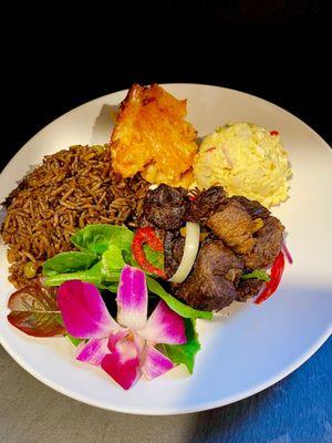 Griot/fried pork bits with black rice, baked mac and cheese, potato salad and garden salad