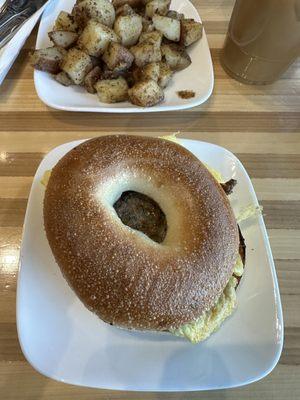 Egg and sausage sandwich on a bagel with garlic butter potatoes